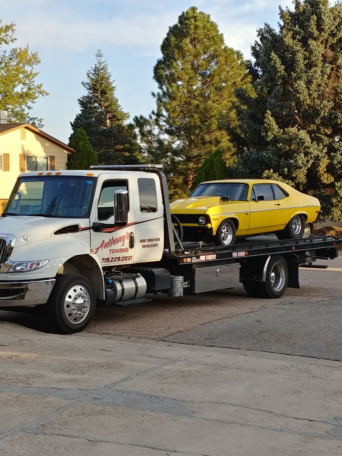 Anthony's Towing flatbed transporting a classic yellow muscle car in Colorado Springs — 40+ years of damage-free vehicle transport