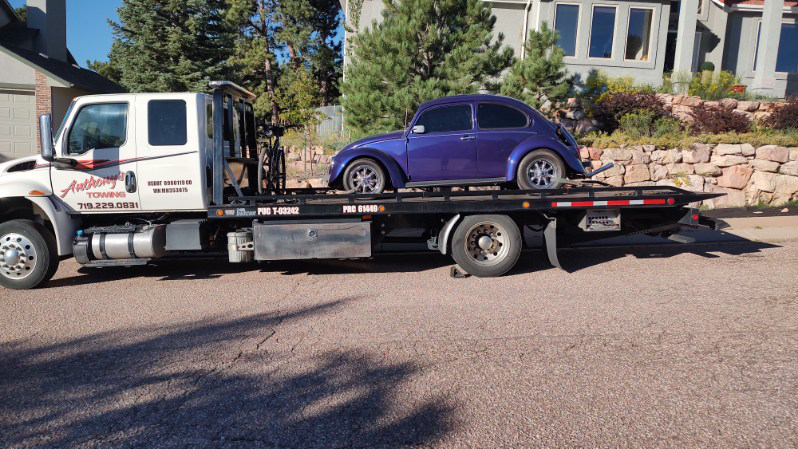 A blue Volkswagen Beetle safely secured on Anthony's Towing tow truck in a residential area thanks to prompt and reliable towing during the holidays.