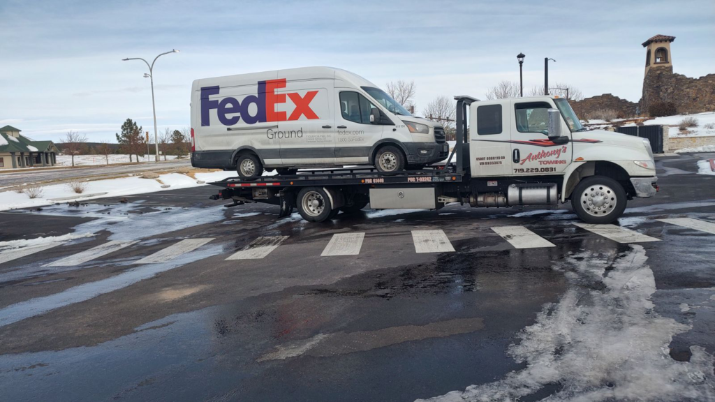 A reliable Anthony's Towing tow truck securely transports a FedEx truck