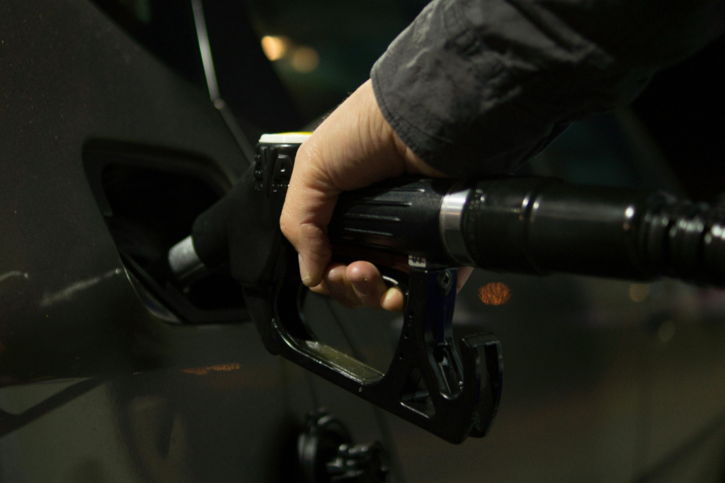  A close-up shot of a person holding a fuel pipe while filling up gas in a car, a routine act central to maximizing fuel efficiency.