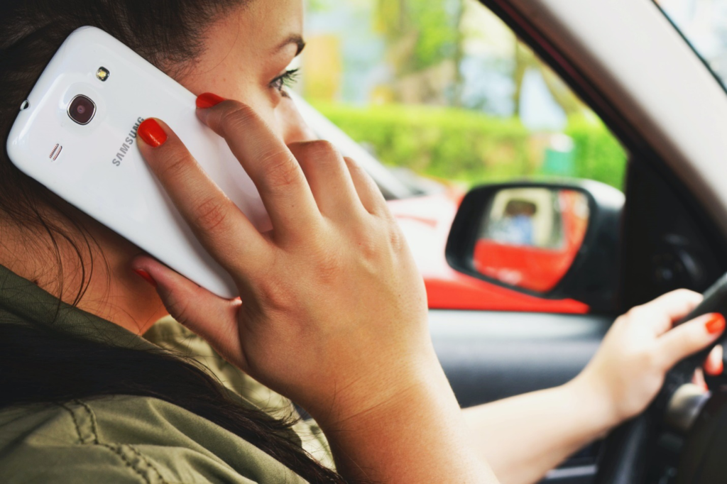 Woman sitting in a car using a white Samsung smartphone to call a wrecker service