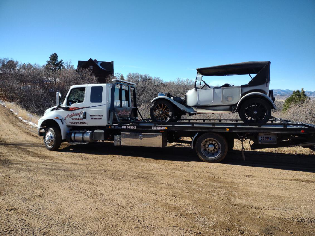 A reliable Anthony's Towing tow truck moves a vintage car, emphasizing reliable towing solutions.